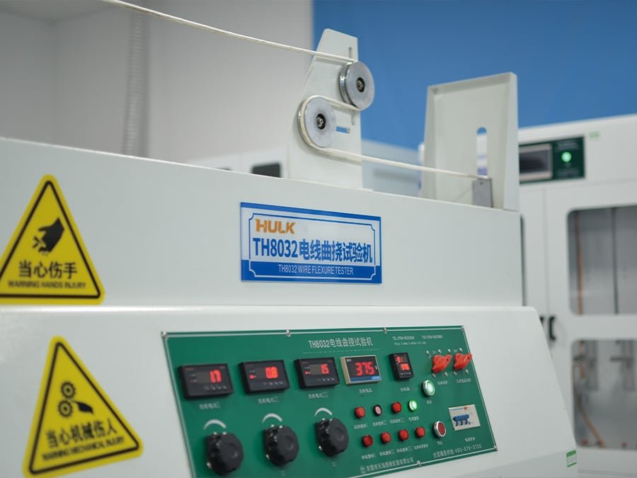 A close-up of the TH8032 Wire Flexure Tester control panel and mechanism, with a HULK cable undergoing high-frequency reciprocating bending; this test simulates repeated flexing motions to verify the conductor's resistance to fatigue and breakage in applications involving frequent movement or vibration.