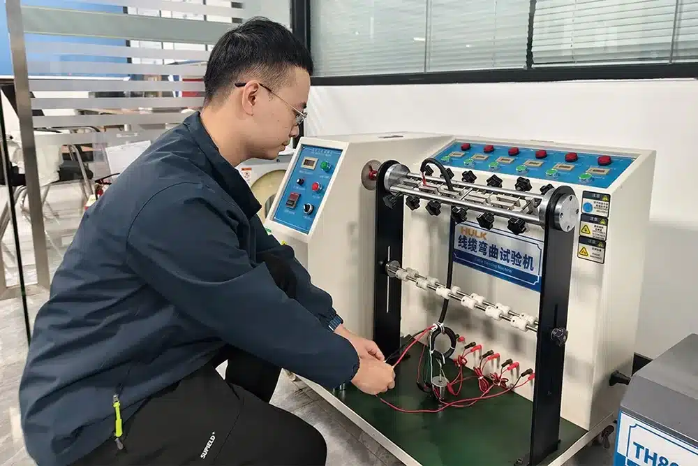 HULK engineer setting up cable bending tester to evaluate plug wire durability under repeated flexing, simulating real-world usage for consumer and industrial connectors.