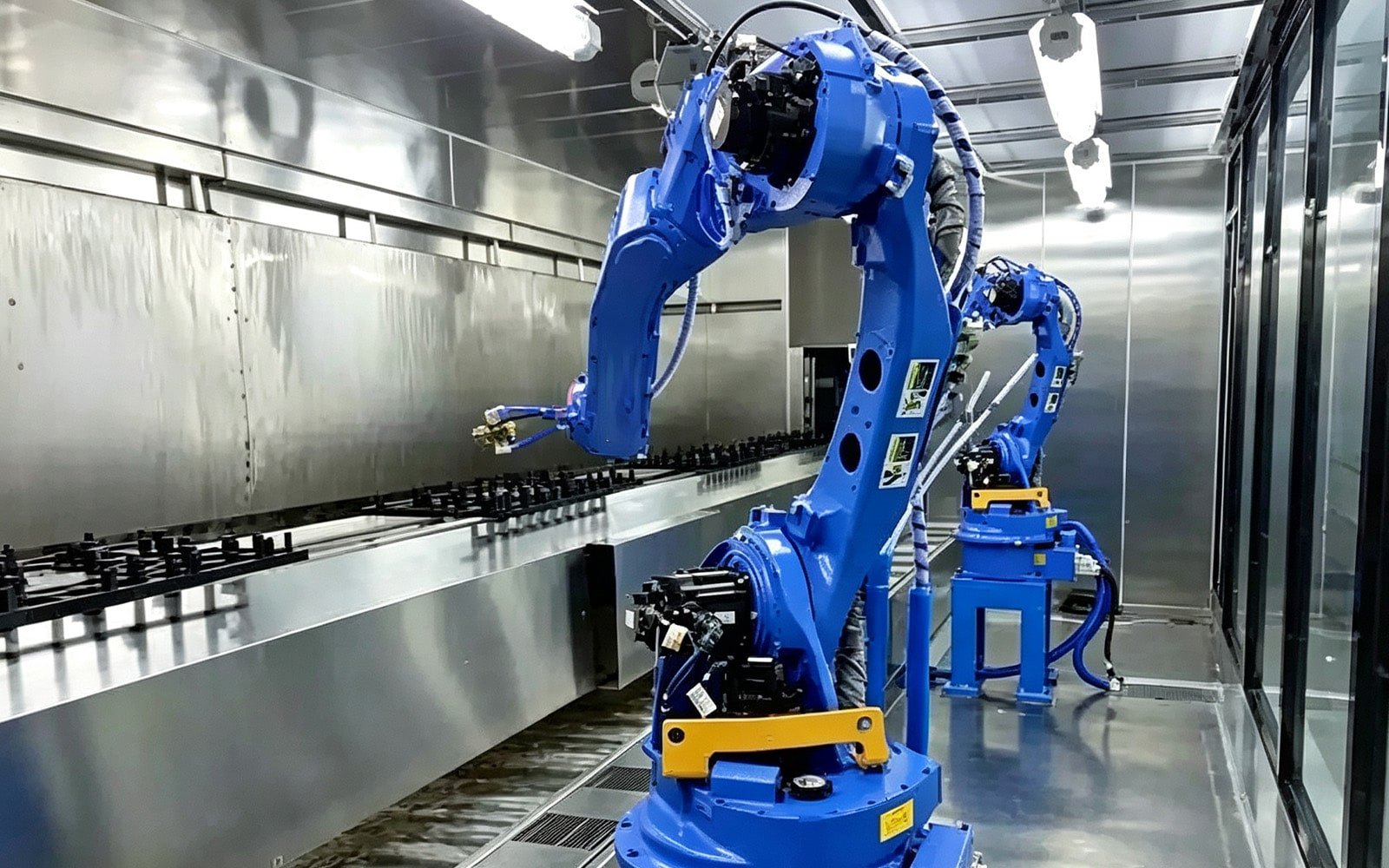 Blue explosion-proof spray painting robots in a sealed paint booth, with HULK high-flex cables routed along their arms; the cables feature chemical-resistant insulation and explosion-proof shielding, ensuring safe and reliable operation in environments with flammable solvents and coatings for automotive or appliance manufacturing.