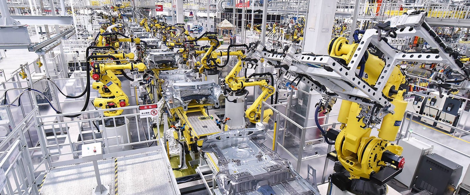HULK high-flex, EMI-resistant cables deployed across dozens of yellow industrial robots in an automotive welding shop; cables endure high vibration and frequent bending while ensuring stable power and data transmission between robots, central control, and welding systems — engineered for system compatibility and long-term reliability in 24/7 high-volume manufacturing.