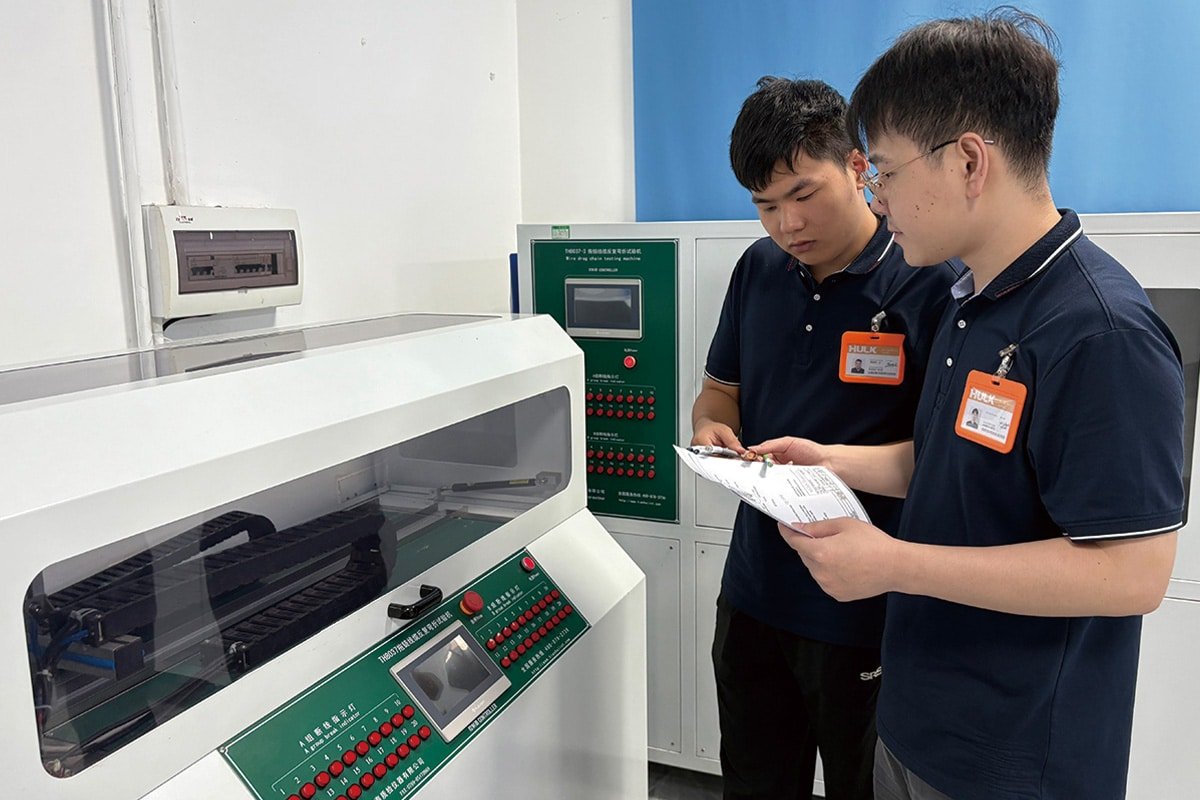 HULK engineers conducting dual verification on TH8037 drag chain cable reciprocating bending tester, ensuring test parameters and cycle counts meet client specifications for automated machinery applications.