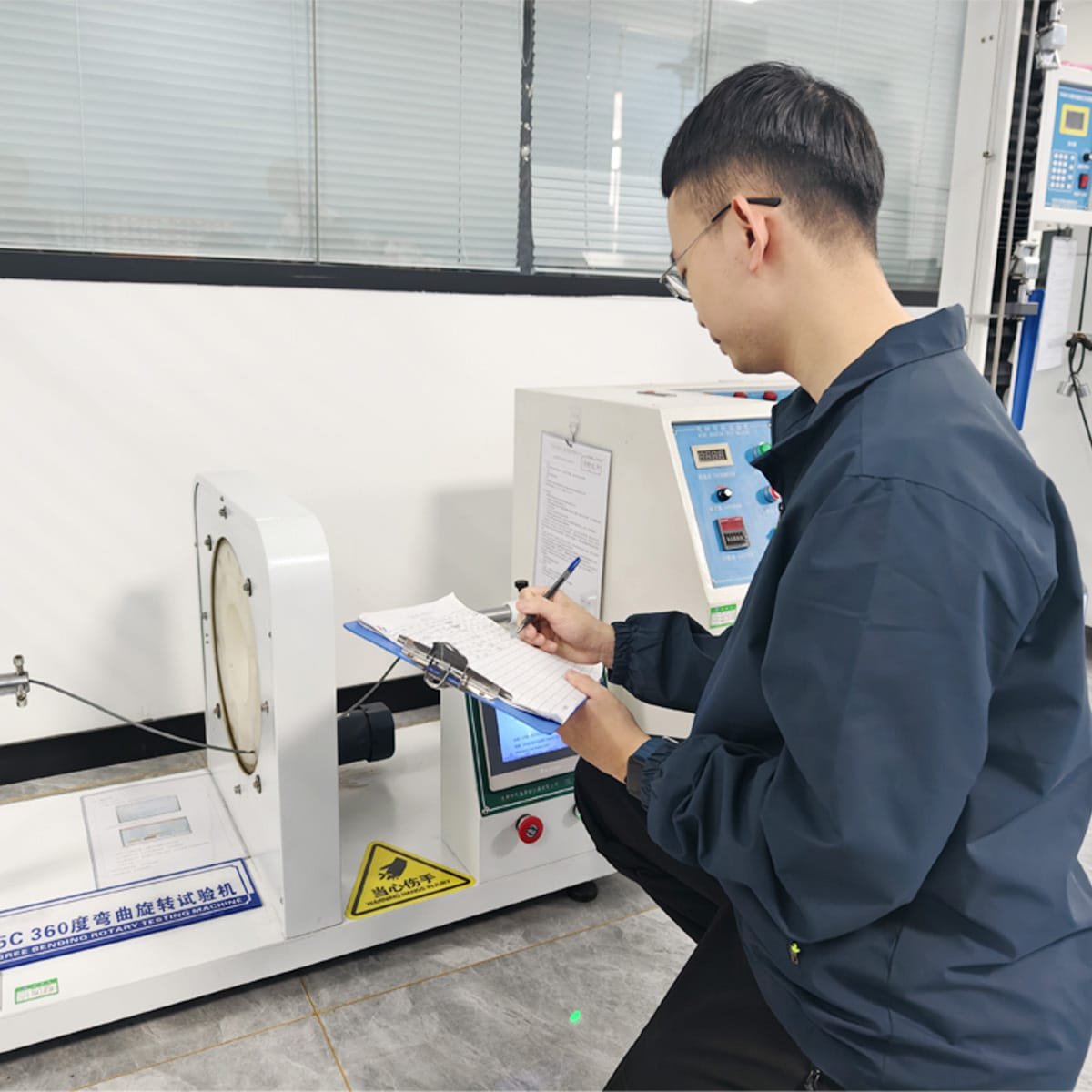 HULK technician recording data during a 360-degree bending rotary test on a cable sample; using specialized machinery to simulate extreme dynamic movement and verify mechanical durability, ensuring the cable withstands millions of bending cycles without failure in drag chain applications.