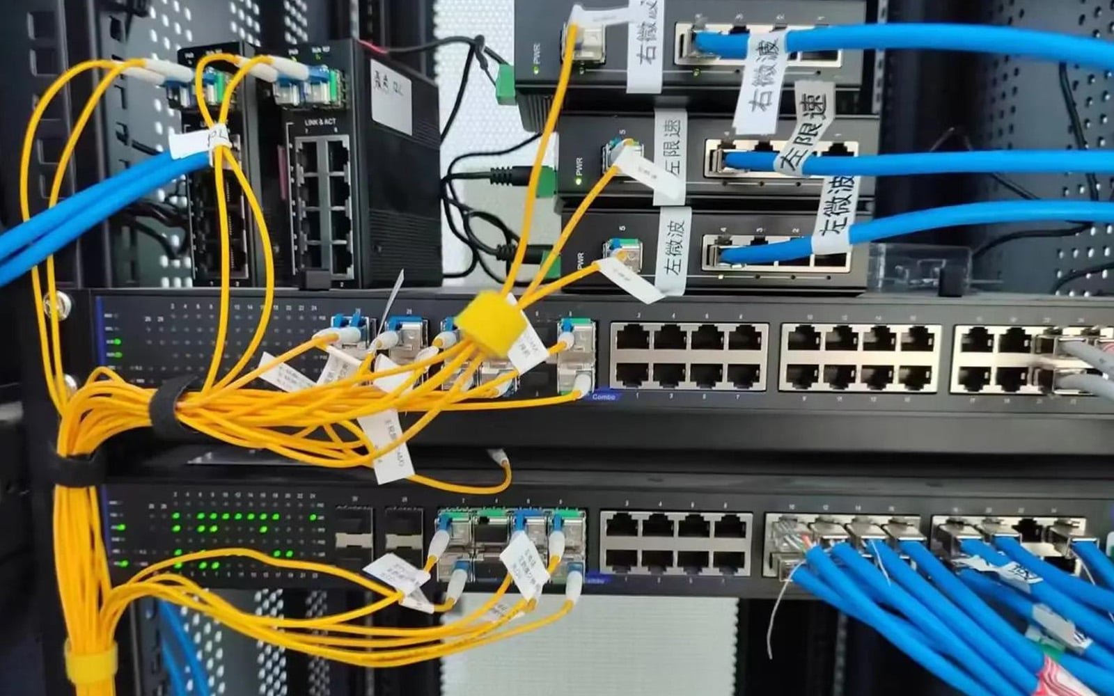 A close-up of an industrial control cabinet with HULK-branded network cabling system; yellow and blue Ethernet cables are neatly routed and labeled with Chinese tags (e.g., “左微波”, “右限速”), demonstrating structured identification and high-density integration for reliable data transmission in smart factory environments.