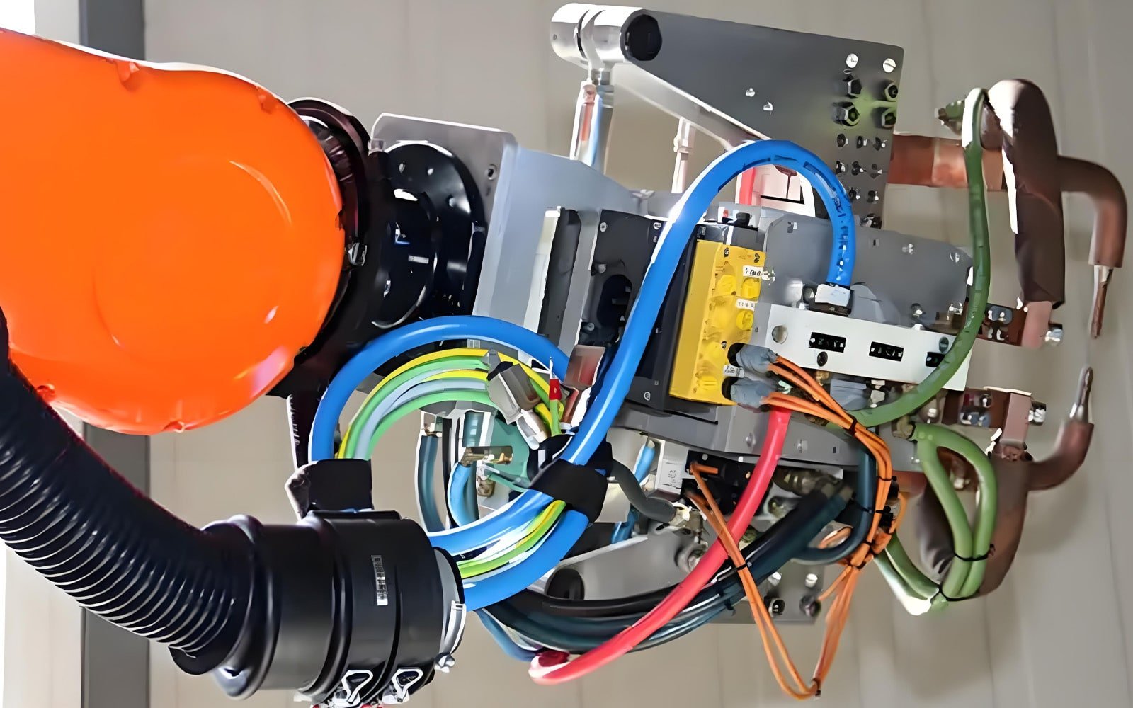 A close-up of an industrial robot’s internal wiring system, featuring bundled HULK high-flex cables in blue, green, red, and orange routed alongside pneumatic tubes and protected by black corrugated conduit; the compact, organized layout demonstrates HULK’s ability to integrate seamlessly into tight robotic joints while maintaining signal integrity and mechanical durability under continuous motion.