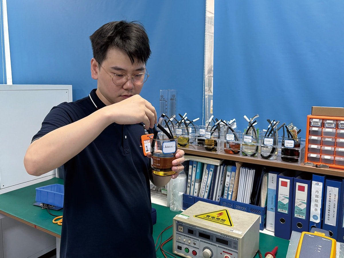 HULK engineer conducting chemical resistance testing by immersing cable samples in oil solutions, verifying material durability against corrosion and swelling in harsh industrial environments.