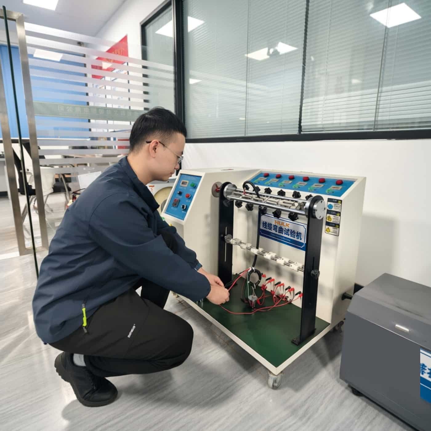 HULK engineer setting up cable bending tester to evaluate plug wire durability under repeated flexing, simulating real-world usage for consumer and industrial connectors.