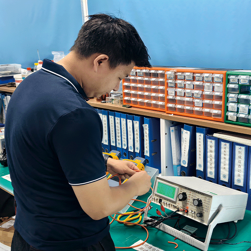 A HULK technician conducting precise electrical resistance measurements using a digital micro-ohmmeter in a well-organized laboratory; background shelves feature labeled component bins and blue binders for inspection reports and process records, highlighting the company's rigorous approach to material verification, data traceability, and detailed quality documentation.