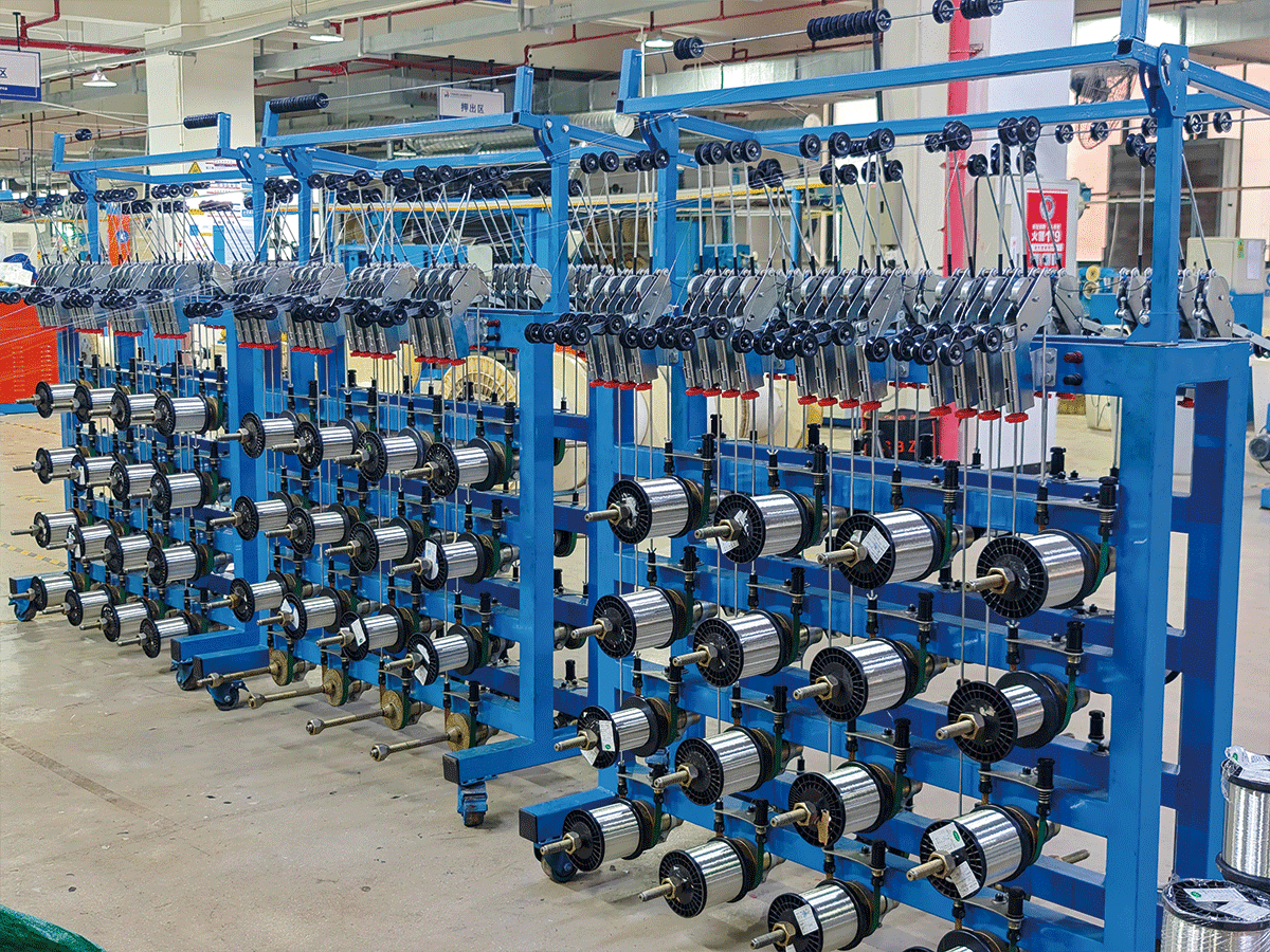 HULK factory stranding production area featuring rows of blue automated machines with multiple silver copper wire spools; the setup ensures precise multi-wire twisting for consistent conductor structure, directly supporting high-conductivity and mechanical durability in industrial cables.