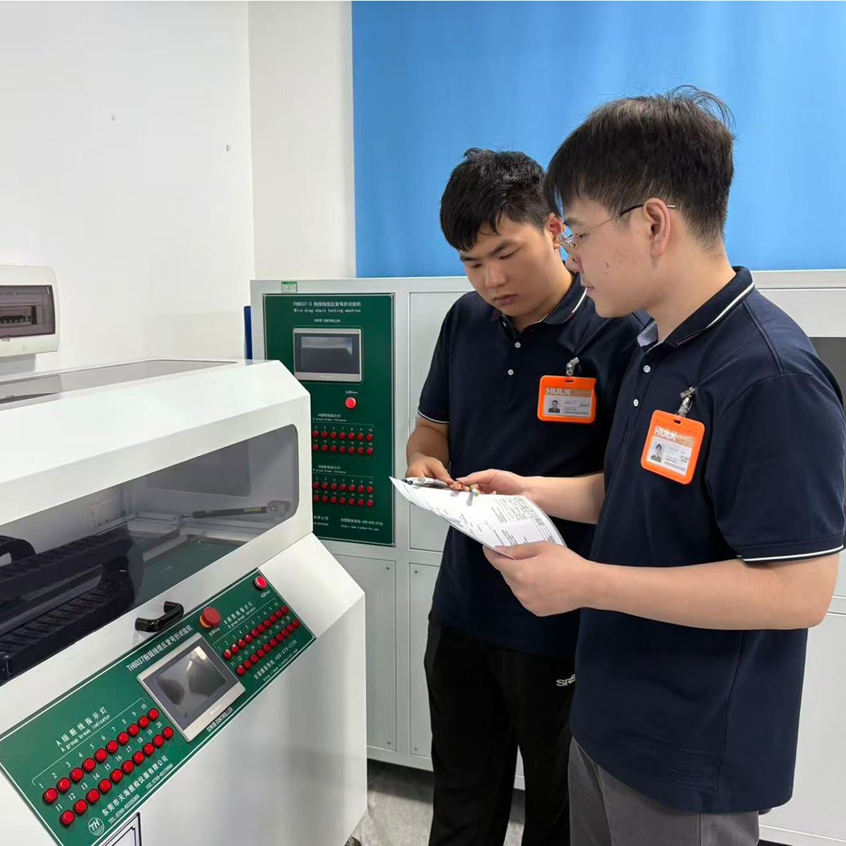 HULK engineers reviewing test data beside TH8037-3 Thermal Wire Repeated Bending Tester in a lab; equipment simulates high-temperature and high-frequency flexing conditions to evaluate long-term aging performance of cables — validating HULK’s commitment to reliability under combined thermal and mechanical stress for industrial, automotive, and new energy applications.