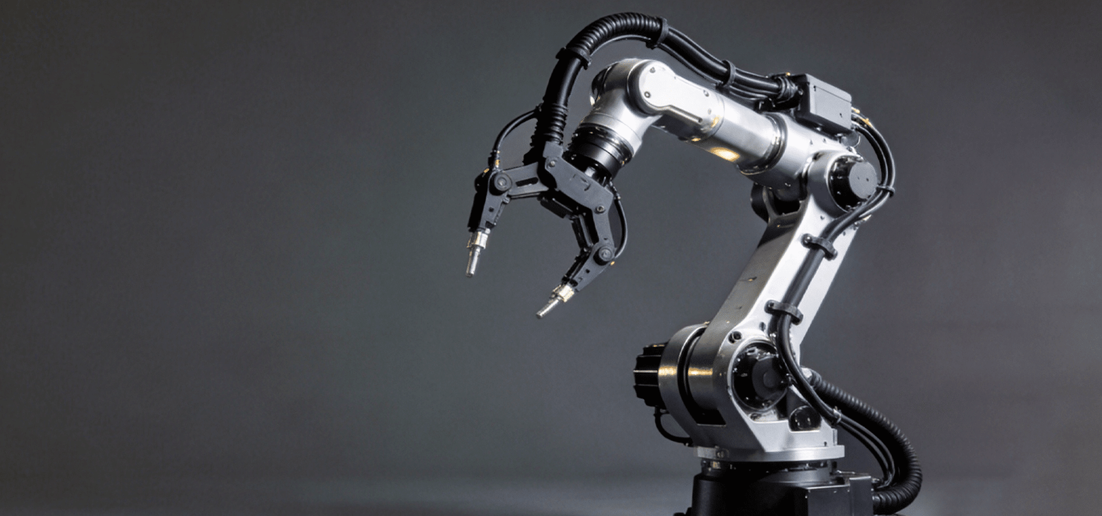 A silver industrial robotic arm in action against a dark background, featuring HULK high-flex black corrugated cables integrated along its joints; the cables demonstrate extreme flexibility and durability while enduring complex multi-axis movements, highlighting their suitability for advanced automation and robotics applications.