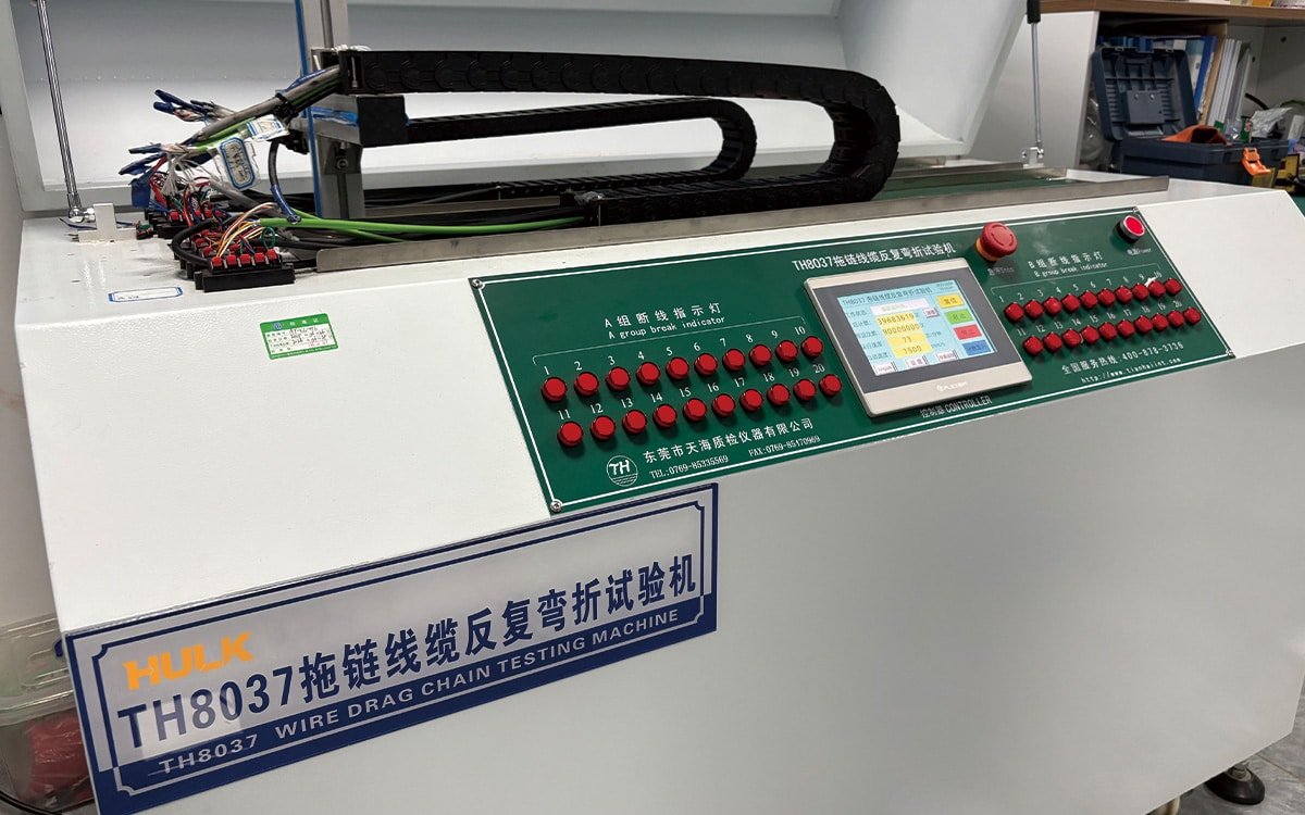 Front view of the HULK TH8037 Wire Drag Chain Testing Machine, featuring a green control panel with touchscreen interface, 20 red break-indicator buttons for A/B groups, and emergency stop — used to validate cable durability under repeated bending cycles in industrial drag chain applications, ensuring reliability before shipment.