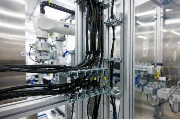 Professional view of high-performance halogen-free cables neatly installed in a modern factory control panel with robotic equipment in background, highlighting clean industrial cabling for safety and reliability in automation projects