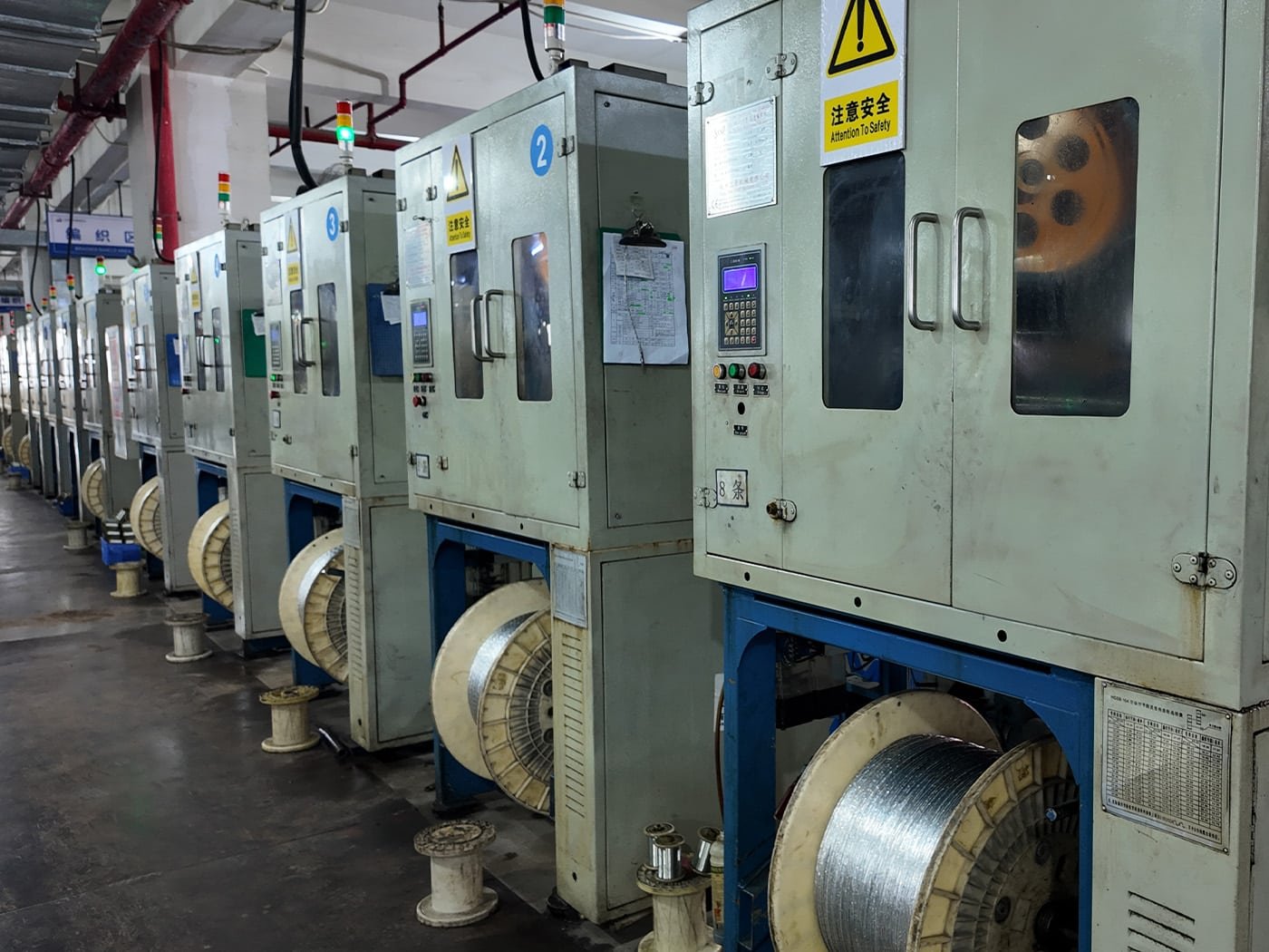 Hulk Cable braiding shield production area with multiple numbered braiding machines and large metal wire spools, demonstrating scalable manufacturing of EMI-shielding layers for industrial control and automation cables