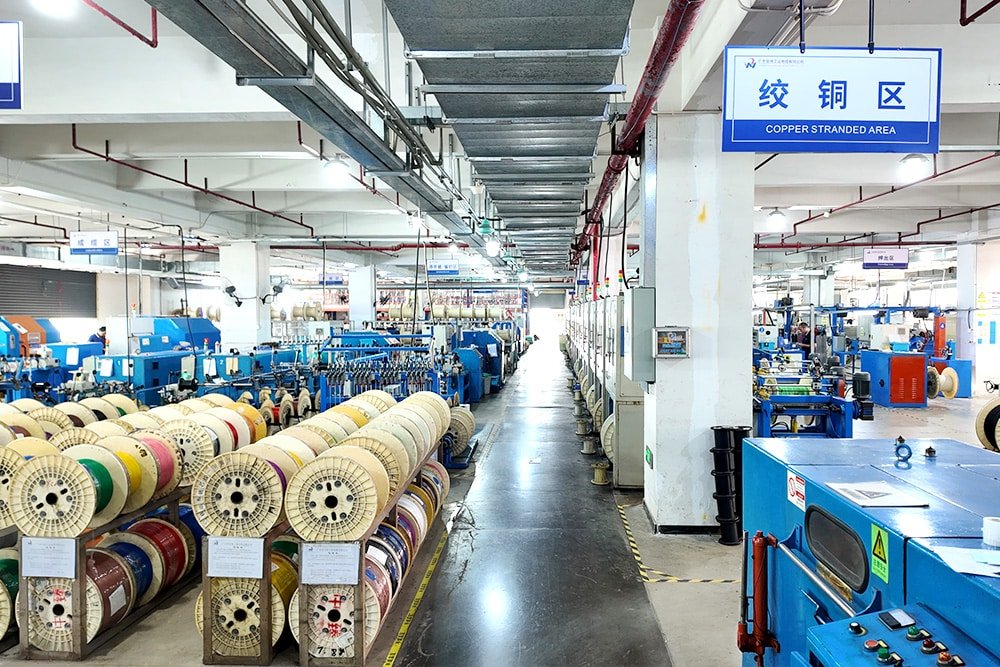 Hulk Cable cable stranding area with rows of blue stranding machines and stacked finished cable spools in organized factory layout