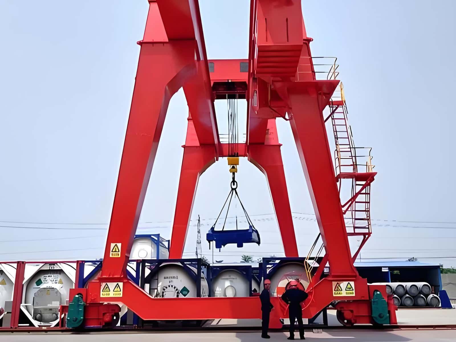 Hulk Cable heavy-duty red gantry crane lifting equipment with safety personnel supervising in outdoor cable storage yard