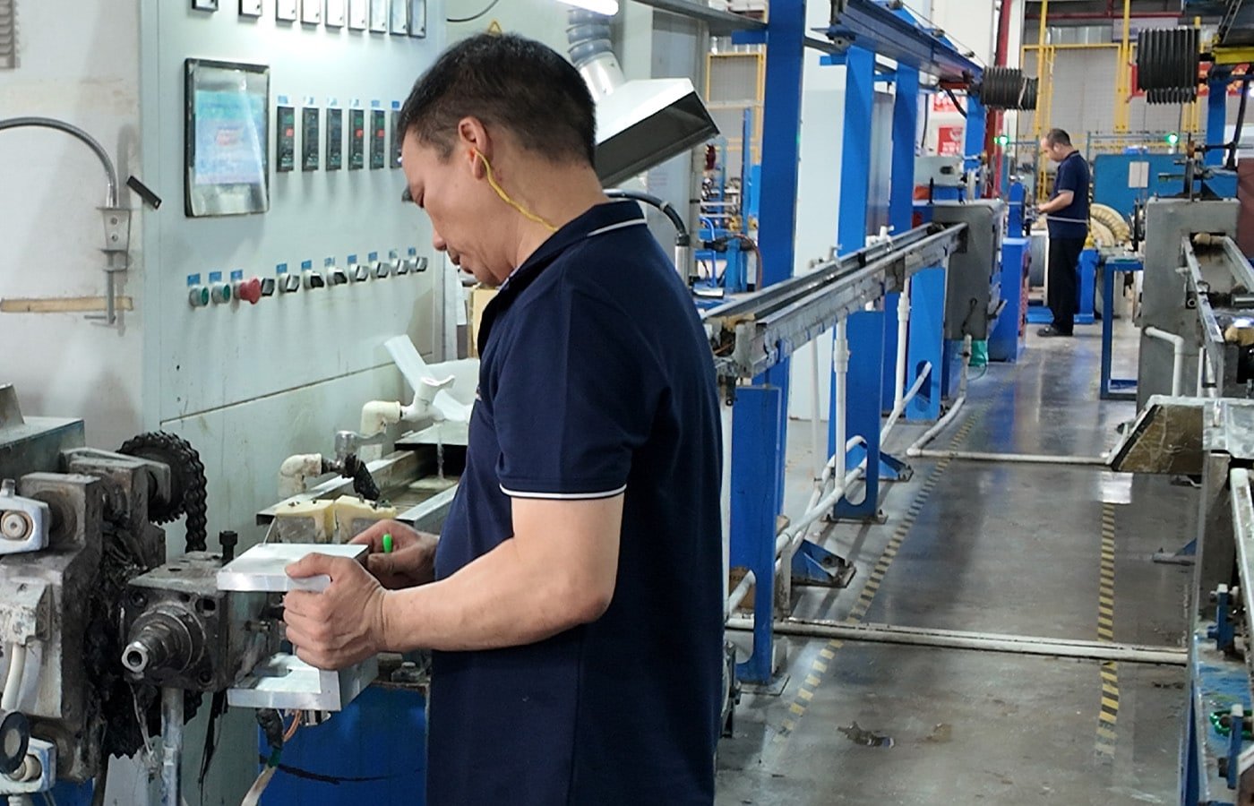 Hulk Cable manufacturing facility showing quality control technician inspecting cable components on production line with automated extrusion and stranding equipment in background, emphasizing precision engineering and in-house manufacturing for industrial-grade cables