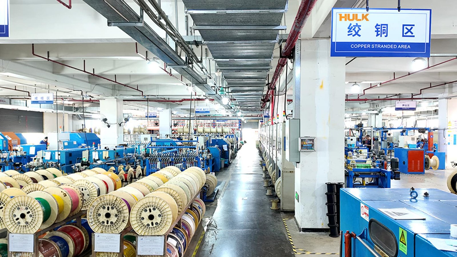 Hulk Cable factory interior showing the Copper Stranded Area with rows of blue stranding machines and organized racks of colorful wire spools, demonstrating large-scale conductor manufacturing and standardized workshop management