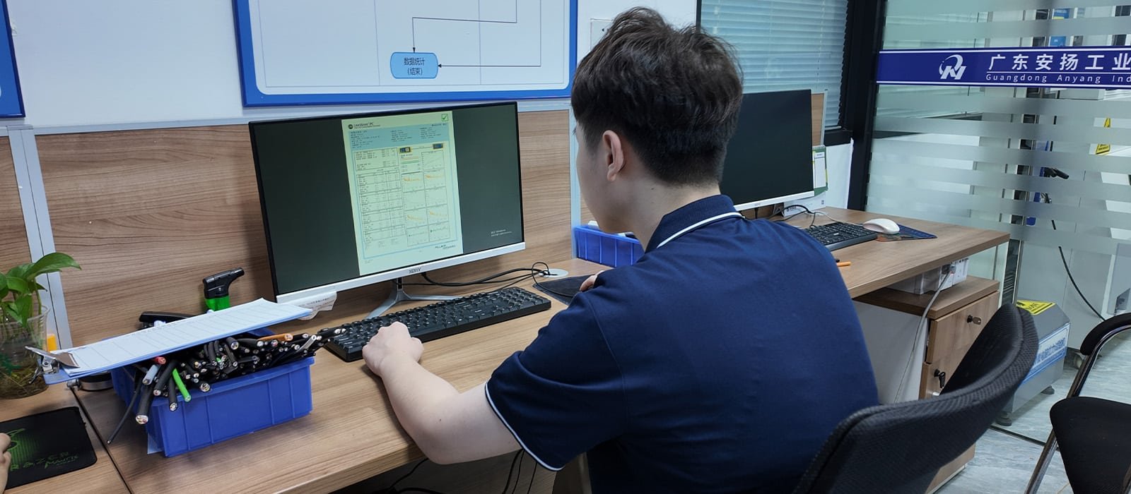 Hulk Cable R&D engineer analyzing test data on computer with cable cross-section samples nearby, demonstrating data-driven design and iterative optimization for industrial cable development