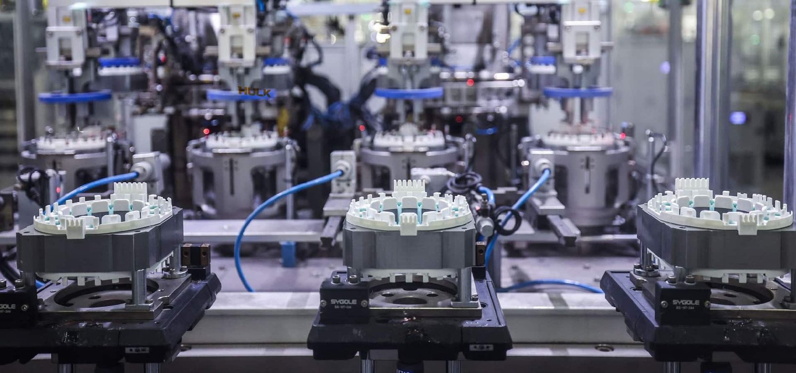 Hulk Cable high-flex cabling solution for multi-station rotary assembly line, featuring blue shielded cables routed along mechanical arms for stable power and signal transmission under high-frequency motion and oil exposure