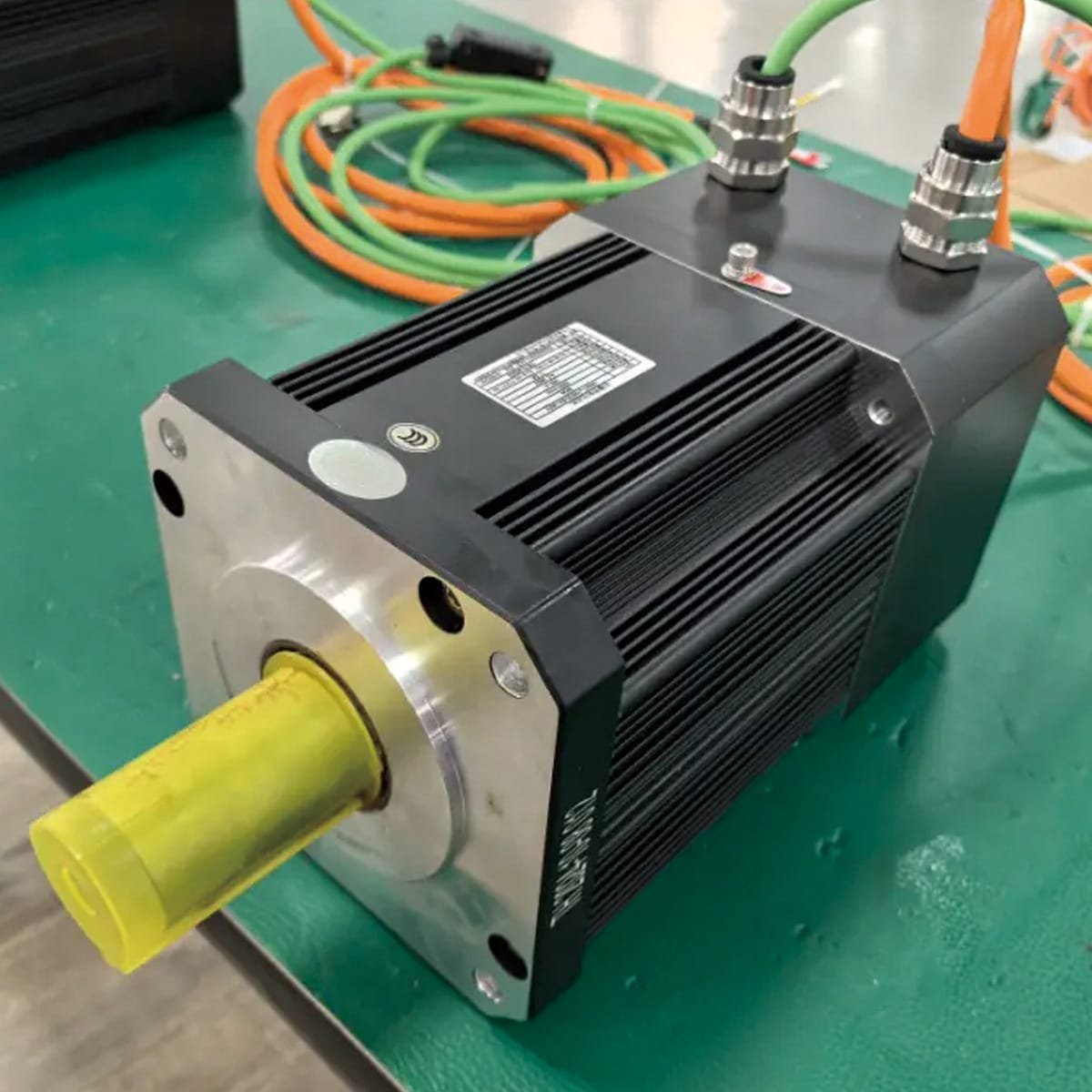 Hulk Cable servo motor system with orange power cable and green encoder feedback cable connected via metal waterproof connectors, designed for high-precision motion control in CNC machines and robotic joints