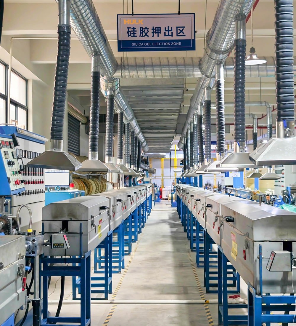 Hulk Cable silica gel ejection zone with blue-supported extrusion machines and overhead ventilation ducts in factory workshop