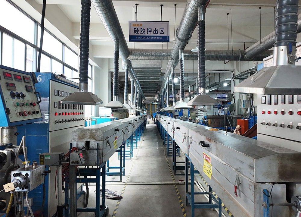Hulk Cable silica gel ejection production line with multiple extrusion machines, control panels, and overhead ventilation ducts, demonstrating high-temperature precision manufacturing of silicone-insulated industrial cables