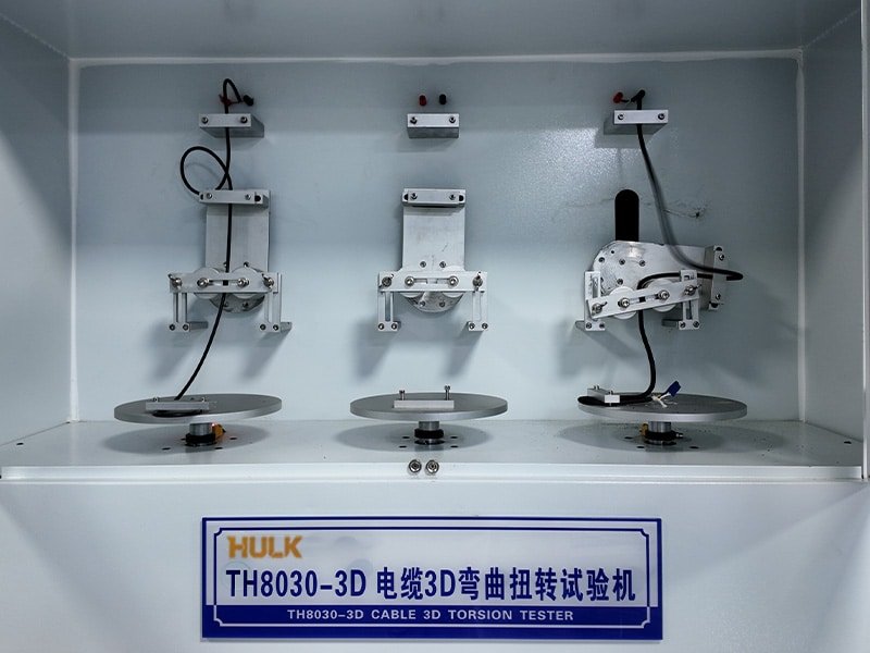 Hulk Cable TH8030-3D 3D torsion tester with three cable samples undergoing simultaneous bending and twisting motion inside a white test chamber, highlighting advanced simulation of complex dynamic stresses for robotic and drag chain applications