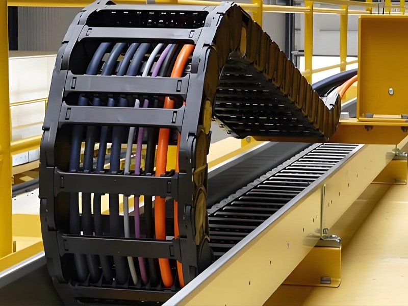 Close-up of black engineering plastic drag chain with multi-colored Hulk cables (orange, purple, blue) routed inside, demonstrating high-flexibility and durability for repeated bending in industrial automation systems