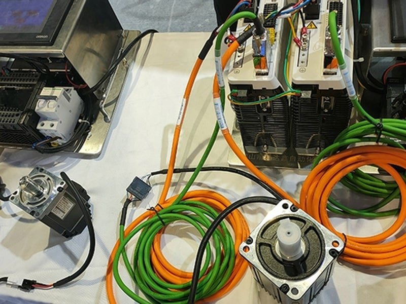 Hulk Cable servo system setup with orange power cables and green encoder feedback cables connecting servo motors to drives, demonstrating precise motion control wiring in industrial automation applications
