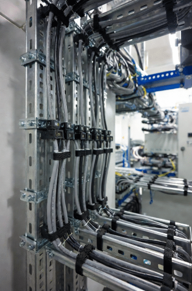 Close-up of neatly installed halogen-free LSZH cables in stainless steel trays in an industrial control room or data center, demonstrating professional fire-safe cabling practices for equipment-dense environments