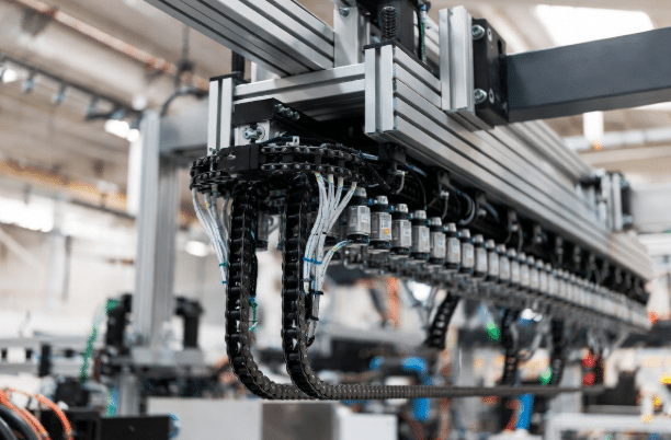 Professional view of long-travel gantry in industrial setting with gliding drag chain energy chain system carrying high-flexible cables along extended horizontal axis inside guide trough for material handling automation