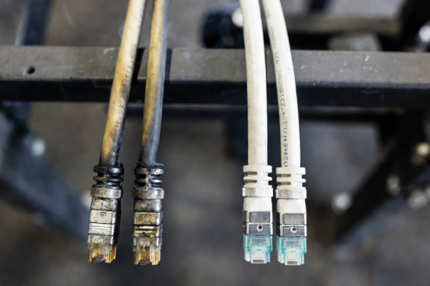 Side-by-side realistic comparison of standard PVC jacket versus halogen-free LSZH jacket on industrial Ethernet cables, illustrating fire safety and corrosion resistance differences in industrial settings