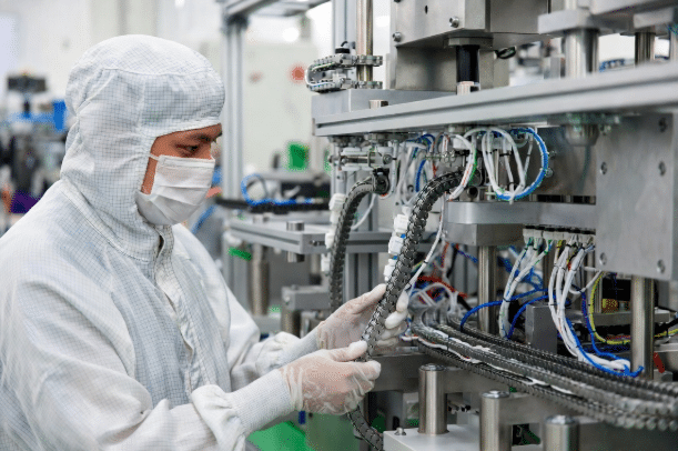 Factory technician inspecting and adjusting custom drag chain cables installed on high-speed packaging and assembly machine, demonstrating professional quality control and integration