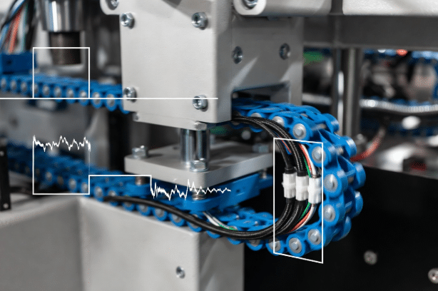 Industrial drag chain cable carrier in motion with high-flex shielded signal cables, overlaid with oscilloscope waveforms showing clean signal versus noisy signal with dropouts in automation equipment